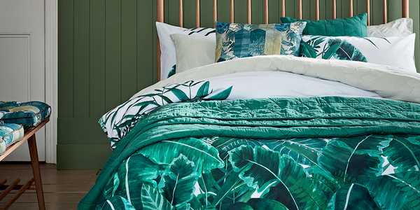 Wooden bed with green leafy bedding.